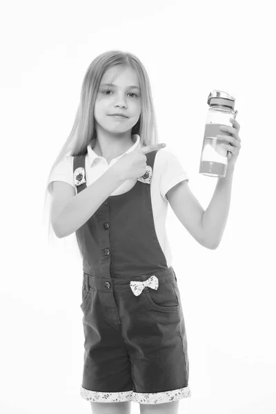 Mädchen mit lächelndem Gesicht posiert mit einer Flasche Wasser, isoliert auf weißem Hintergrund. Mädchen mit langen Haaren, die auf eine Flasche mit Wasser zeigen. Wasserhaushaltskonzept. Mädchen sorgt sich um Gesundheit und Wasserhaushalt — Stockfoto