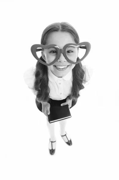 Chica lindo corazón grande en forma de gafas aisladas fondo blanco. La ropa de uniforme escolar de niña sostiene el libro. De vuelta al concepto escolar. Lindo e inteligente. Niño desgaste escuela uniforme inteligente niño sonriendo cara — Foto de Stock