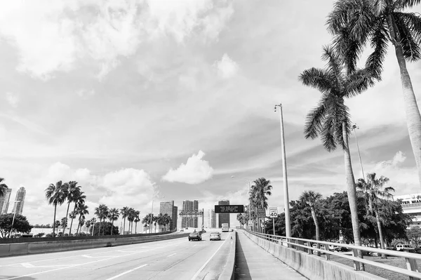 Autobahn oder Fahrbahn mit Autos und Skyline von miami, USA. Straße mit Verkehrsschildern für Transportfahrzeuge und Palmen am bewölkten blauen Himmel. Konzept der öffentlichen Infrastruktur. Anreise mit dem Auto — Stockfoto