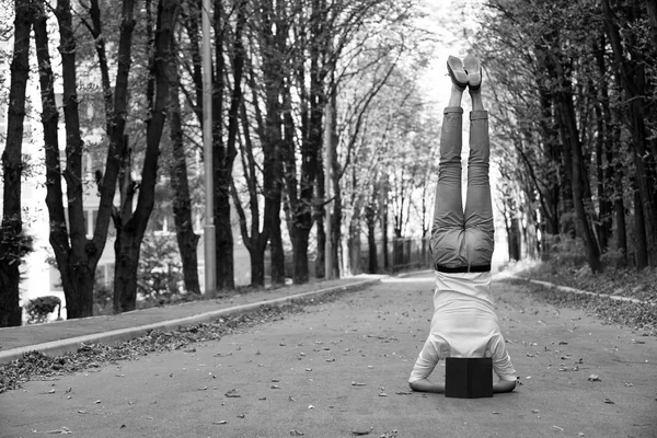 O homem fica em pé na estrada do parque. Estudante com livro de cabeça para baixo no outono ao ar livre. Equilíbrio da vida profissional. Educação e conhecimento. Yoga exercício headstand e esporte — Fotografia de Stock