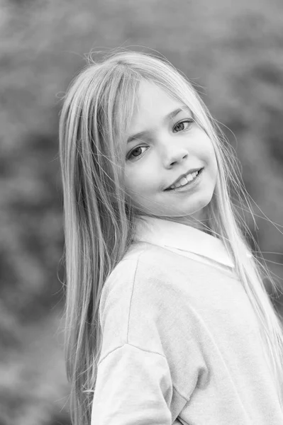 Menina sorrir com cabelo loiro longo. Criança com rosto bonito ao ar livre. Criança de beleza com aparência fresca e pele. Look de beleza e cuidados com a pele. Infância feliz e acolhimento de crianças — Fotografia de Stock