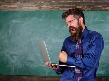 Yenilikçi öğretmen laptop ile agresif yavaş hızlı internet bağlantısı hakkında deli gider. Öğretmen adam modern dizüstü kara tahta arka plan sakallı. Yavaş yavaş Internet onu rahatsız edici. Yavaş internet tarafından rahatsız