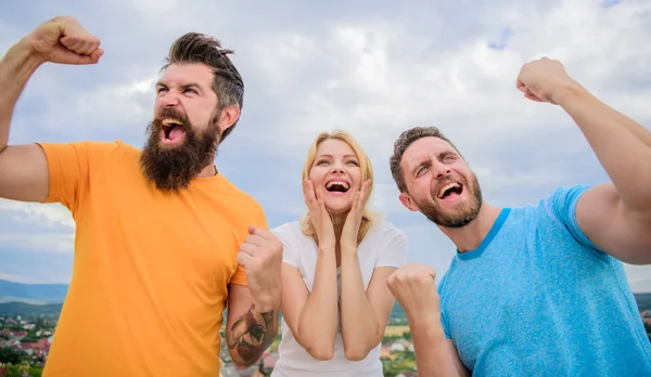 Unbelievable luck. Behavior successful team. Emotional explosion. Threesome winners happy with raised fists. We are winners. Woman and men look emotional successful celebrate victory sky background