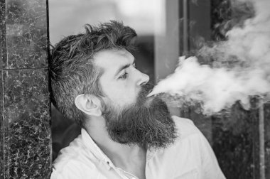 Yan görünümü çekici hipster bir kentsel bağlam ayakta mermer kaplama ile duvar yanındaki adam. İyi görünüyor sakallı adam sigara elektronik sigara, alışkanlıkları ve gençlik moda