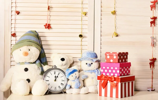 Kardan adamlar, oyuncak ayılar ve çalar saatin yanındaki kutular.