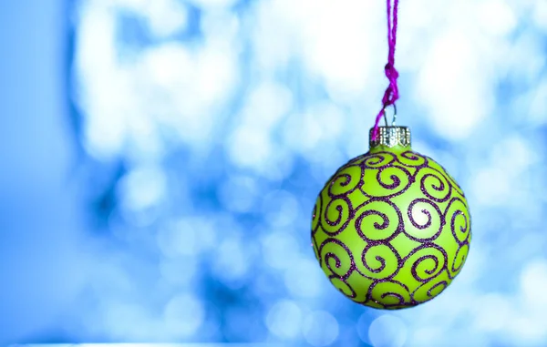 Koncept ornament. Vánoční dekorace nebo hračka pro vánoční strom s třpytivými detaily, kopírovat prostoru. Slavnostní dekorace pro vánoční strom, zelená koule s dekorem třpytky na modré rozostřeného pozadí — Stock fotografie