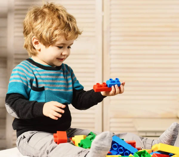 Menino joga com lego no fundo da parede de madeira. — Fotografia de Stock