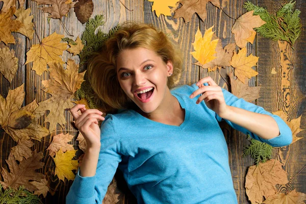 Fall atmosphere attributes. Woman pretty lady enjoy season hold autumn dry leaves. Girl blonde lay on wooden background with orange leaves top view. Fall and autumn season concept