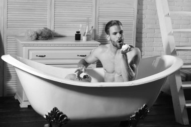 Sakallı adam banyo yapıyor ve köpük üflüyor.