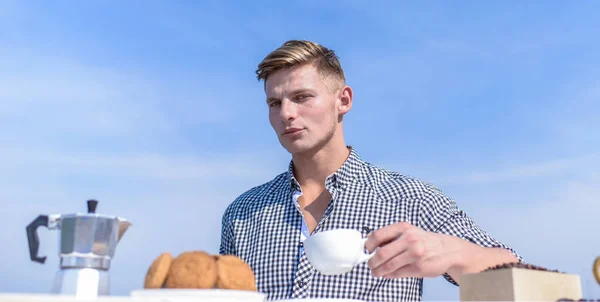 Man hold cup of coffee sky background. Man muscular athlete drink morning coffee. Pleasant morning outdoors. Daily traditions. Breakfast outdoors weekend tradition. Guy enjoy great beginning of day