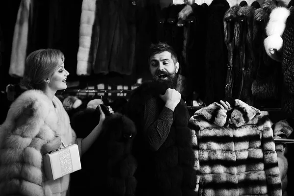 Seller with beard and woman buy furry coat.
