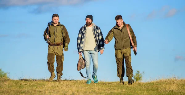 Un pasatiempo brutal. Chicos reunidos para cazar. Grupo de hombres cazadores o guardabosques naturaleza fondo cielo azul. Los hombres llevan rifles de caza. La caza como hobby y ocio. Cazadores con armas caminan soleado día de otoño —  Fotos de Stock