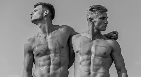 Hommes musclé avec torse sexy nu, ciel sur fond. Concept de vente. Athlètes avec inscription vente sur les coffres musculaires sexy. Les athlètes sur les visages sérieux câlins et regarde les côtés opposés — Photo