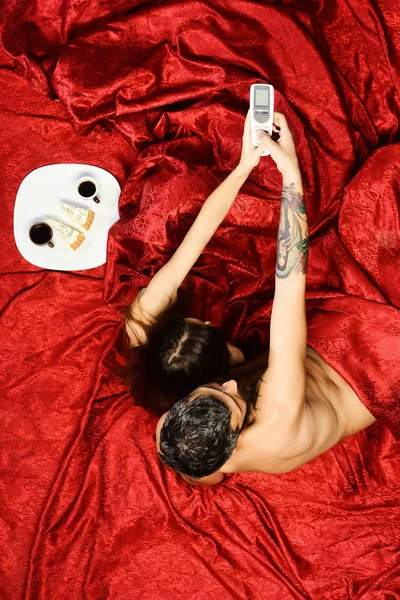 Çift desenli kırmızı çarşaf üzerinde aşık. Erkek ve kadın — Stok fotoğraf