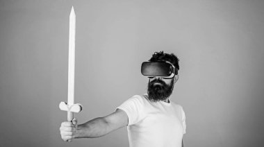 Oyun kavramı. Adam kafa monte görüntü tutar kılıç, Vr. Hipster oyunda ciddi yüz mücadele oyun ile zevk oyna sanal gerçeklik. Vr gözlük, açık mavi renkli sakallı