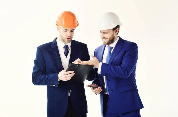 Os parceiros de negócios olham para o plano de construção. Engenheiros com barbas e rostos felizes. Arquitetos discutem projeto. Empreendedor e arquiteto parecem confiantes. Construção, engenharia, conceito de sucesso — Fotografia de Stock