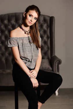 Yüksek sandalyedeki meraklı yüzlü kadın. Biçim ve moda