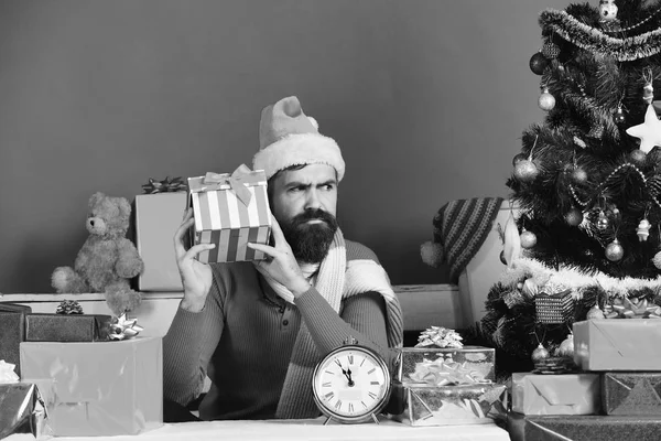 Santa drží dárkovou krabici. Muž s plnovousem a zvědavou tváří — Stock fotografie