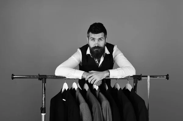 Designer leans on clothes hangers with suits