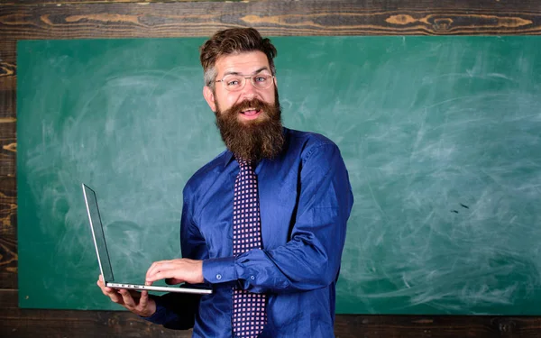 Insegnante uomo barbuto con sfondo lavagna portatile moderno. Educazione online. Educazione alla tecnologia digitale. Educazione tecnologica moderna. Hipster insegnante indossare occhiali e cravatta tiene laptop — Foto Stock