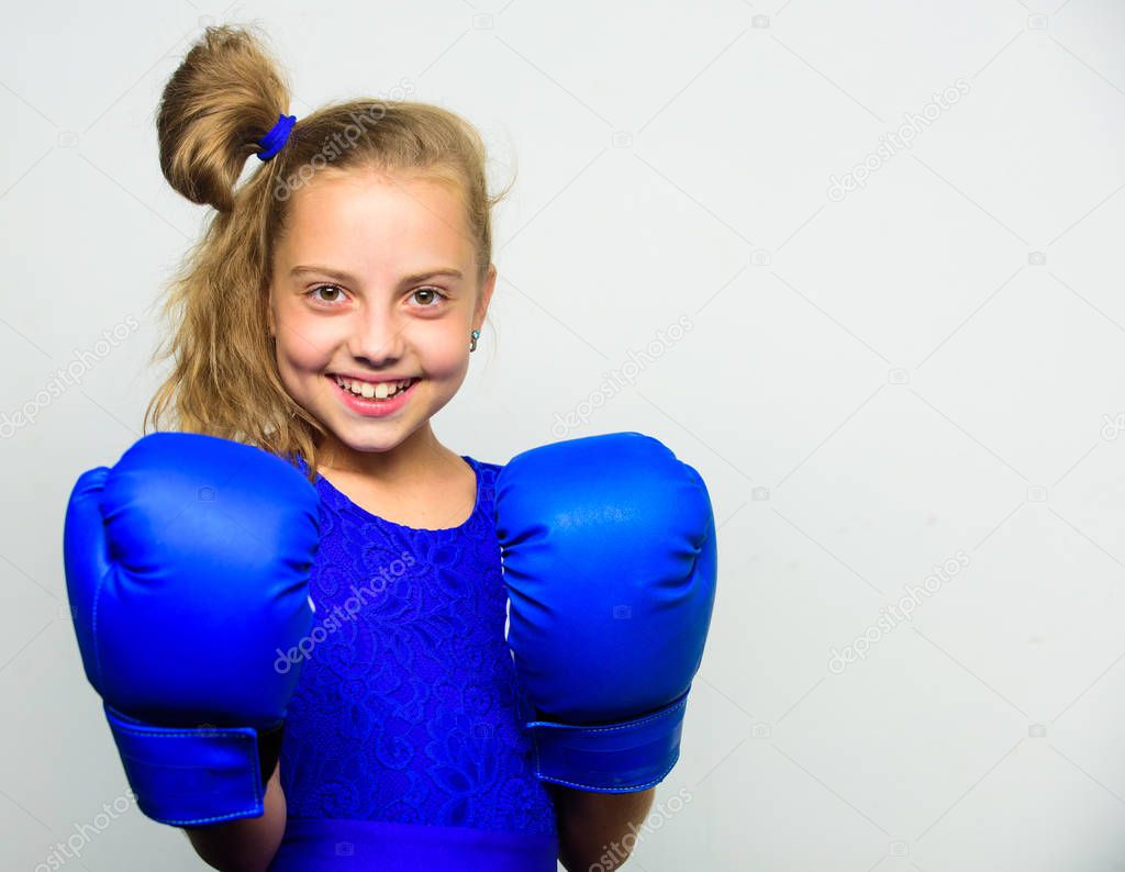 Girl child strong with boxing gloves posing on grey background. She feels strong and independent girl. Sport upbringing for girls. Feminist movement. Strong child concept. Kid strong and healthy