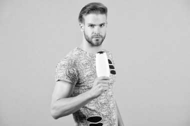 Adam kesin yüz şampuan şişesi, gri arka plan tutar. Adam saç şampuan ile yıkandıktan sonra tazelik tadını çıkarın. Adam saç modeli ile şişe şampuan, kopya alanı tutar. Saç Bakımı ve güzellik malzemeleri kavramı