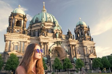 Berlin Katedrali 'nin önünde güneş kremi sürerek oturuyor.