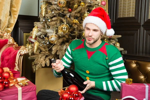 O homem celebra a festa de ano novo. Papai Noel abrir garrafa de champanhe na árvore de Natal. A festa está perto, dá um grande aplauso. Tenha um ano novo simplesmente bonito — Fotografia de Stock