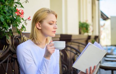 Kadın açık havada içki kafe teras vardır. Daha fazla bilgi için fırsat bulmak. Kız okuma bestseller kitap popüler yazar tarafından ise kahve iç. Kupa kahve ve ilginç kitap en iyi kombinasyonu mükemmel hafta sonu