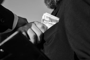 Siyah takım elbise giymiş adam klasör alır rüşvet tutar.