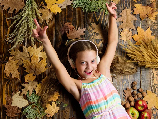 Kid girl wooden background listen music headphones. Child listen music relaxing top view. Autumn melody concept. Happy childhood. Autumn music playlist. Best songs about fall. Enjoy music and relax