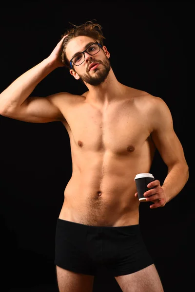 Macho atractivo desnudo chico celebrar café caliente. Tráele placer matutino. Hombre inteligente y sexy con barba y pelo rizado lleva gafas. Hombre sexy torso muscular ofrecen taza de café en la mañana — Foto de Stock