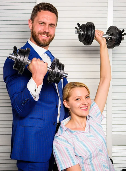 Key to success concept. Man and woman raise heavy dumbbells. Strong powerful business strategy. Boss businessman manager raise hand with dumbbells. Strong business team. Healthy habits in office