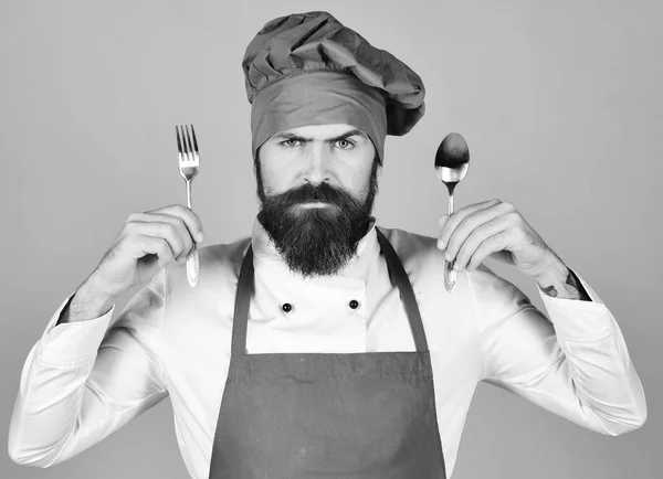 Joven cocinero mostrando cuchara de metal y tenedor —  Fotos de Stock