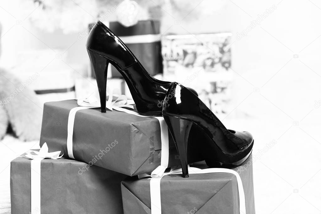 black patent leather shoes standing on large blue christmas gifts or presents on white studio background, selective focu