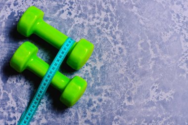 Plastik halterlerin etrafındaki şeritleri ölçüyorum. Yeşil renkli dambıllar.