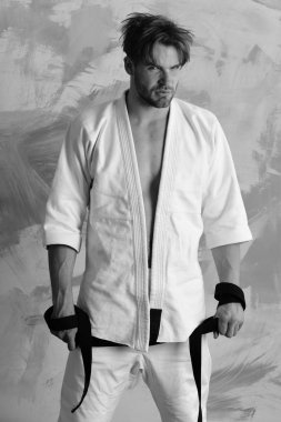 Adam siyah kuşak taşıyan beyaz kimono giymiş.