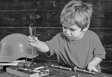 Atölyede oynayan sarışın çocuk. Çocuk bağlama vidalar için ahşap tahta. Konsantre çocuk yeni beceriler öğrenme