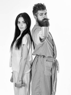Alternatif yaşam tarzı konsepti. Dambılı kız, kahve fincanlı adam. Pijama giyen, bornoz giyen, beyaz arka planda soyutlanmış bir çift. Çift, uykulu yüzlü aile, enerji dolu.