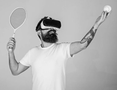 Vr gözlük, gri arka planda sakallı adam. Hipster konsantre yüzündeki spor oyunları için modern teknolojisini kullanıyor. Sanal Tenis kavramı. Vr gözlüklü play tenis raket ve top ile