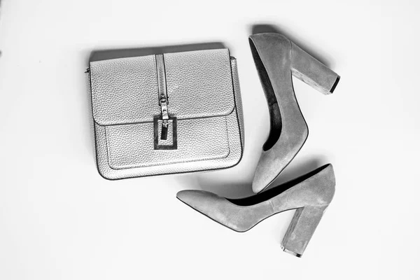 Concepto de accesorios de moda. Calzado para mujer con tacón alto grueso y bolso, vista superior. Par de zapatos de tacón alto de moda y bolso de plata. Zapatos fabricados en ante gris sobre fondo amarillo — Foto de Stock