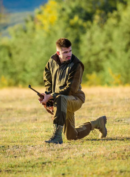 Hunter roupas cáqui pronto para caçar segurar fundo montanhas arma. Troféu de caça. Caçador com espingarda à procura de animais. Caça como passatempo masculino e lazer. Homem carregando rifle de caça — Fotografia de Stock