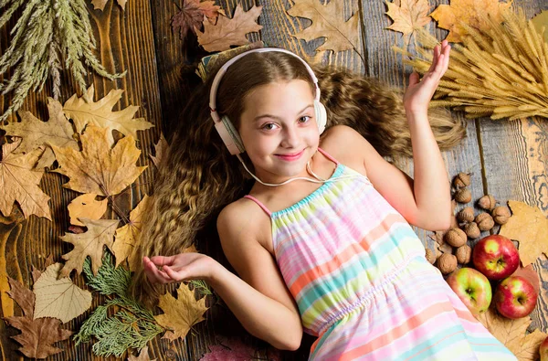 Autumn music playlist. Best songs about fall. Enjoy music and relax. Happy childhood. Kid girl wooden background listen music headphones. Child listen music relaxing top view. Autumn melody concept