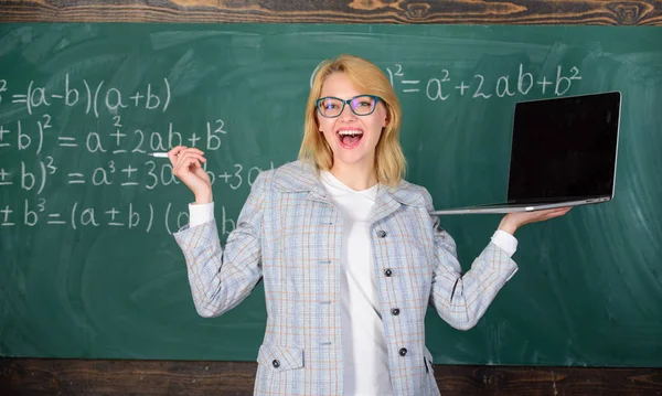 Mujer maestra de usar anteojos sostiene portátil navegar por Internet. Educador alegre dama con portátil moderno navegar fondo pizarra de Internet. La educación es divertida. Concepto de tecnologías digitales — Foto de Stock