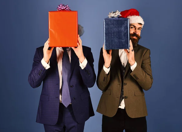 Businessmen hide faces behind red and blue present boxes.