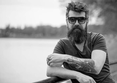 Nehir setin arka plan üzerinde giyer gözlüklü, sakal ve bıyıklı adam. Hippi moda güneş gözlüğü ile kendine güvenen yüzünde. Adam ile şık güneş gözlüğü kendinden emin görünüyor. Erkek moda kavramı