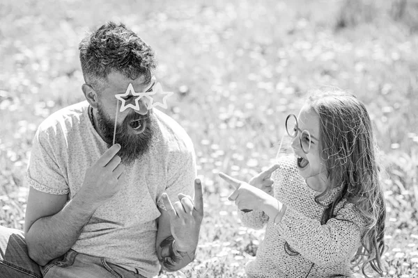 Vater und Tochter sitzen auf einer Wiese auf grünem Grund. Kind und Vater posieren während des Sprechens mit Brillenfotokabinen. Verhandlungskonzept. Familie verbringt Freizeit im Freien — Stockfoto