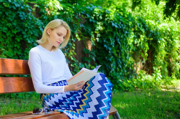 Reading literature as hobby. Books are her passion. Girl sit bench relaxing with book, green nature background. Woman blonde take break relaxing in park reading book. Girl keen on book keep reading