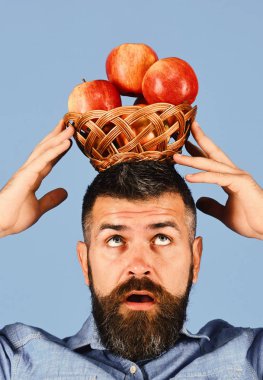 Yoğunlaşmış yüzlü çiftçi kafasında kırmızı elmalar tutuyor..