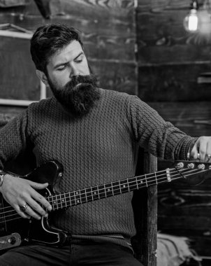 Araç ile poz acımasız bakışla rock müzisyeni. Elektro gitar tuning sakallı adam. Adam şık sakal ve bıyık pişmiş toprak örme kazak ve siyah kot rahatlatıcı müzik konsepti